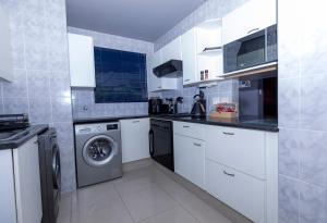 a kitchen with white cabinets and a washer and dryer at 14 Madison Palms East in Johannesburg