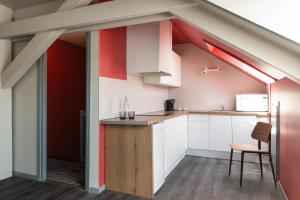 an attic kitchen with white cabinets and a red wall at Hôtel Bristol Reims in Reims