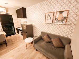 a living room with a couch and a kitchen at Comfy Plum West Gate Condo 1 BR in Ban Bang Krabu