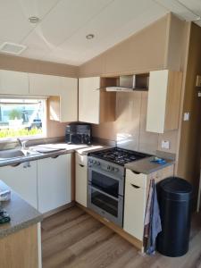 a kitchen with white cabinets and a stove top oven at Stacaravan 161 Capfun camping Bongerd 5 sterren Gezin 5 personen in Tuitjenhorn