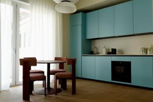 a kitchen with blue cabinets and a table and chairs at Suite Cecilia by Piazza del Lago, Como Center in Como