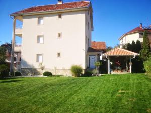 a large white house with a green yard at Vila Amante in Gornja Toplica +5 photos