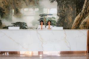 two women standing behind a marble counter in a building at A One Oasis River View Hotel in Phnom Penh