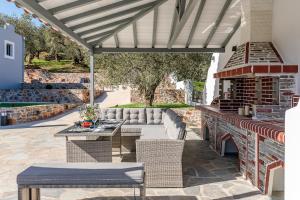 an outdoor patio with a couch and tables and a fireplace at Luxury VILLA RAFAEL in Skopelos Town +155 photos