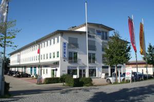 Biały budynek z samochodami zaparkowanymi przed nim w obiekcie Hotel Fresh INN w mieście Unterhaching