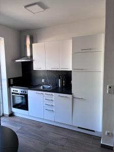 a kitchen with white cabinets and a black counter top at Hügelland Apartment in Elxenbach