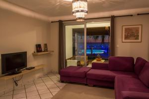 ein Wohnzimmer mit einem lila Sofa und einem TV in der Unterkunft Leu Pied Dans L'Eau in Saint-Leu