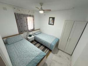 a bedroom with two beds and a ceiling fan at Flamingo Apartman in Torrevieja