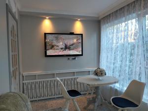 a living room with a table and a tv on the wall at Apartment Sonata in Jūrmala +6 photos