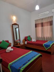a bedroom with two beds and a mirror at Mahaweli Shades in Kandy