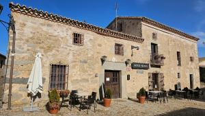 an old building with tables and chairs and an umbrella at La Clerecia de Ledesma in Ledesma