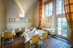 un ristorante con tavoli e sedie bianchi e finestre di Monastery Hotel a Praga