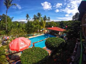a swimming pool with an umbrella next to a resort at BuenaMaria Mountain Resort in Puerto Galera +16 photos