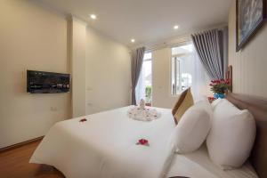 a bedroom with a white bed with white pillows at Hanoi Spoon Boutique Hotel in Hanoi