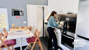 a woman standing in a kitchen with a coffee maker at Recanto das 5 by PontaNegraAzores in Cinco Ribeiras +27 photos