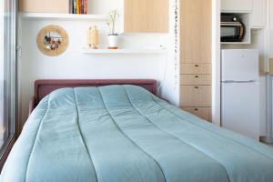 a small bedroom with a bed and a refrigerator at Studio avec balcon Centre Ville in Montreuil