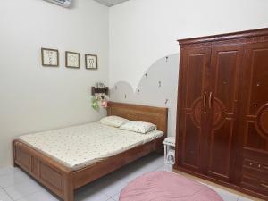a bedroom with a bed and a wooden cabinet at Homestay Mẹ Mít in Cu Chi +15 photos