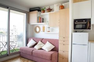 a living room with a pink couch in front of a window at Studio avec balcon Centre Ville in Montreuil +18 photos