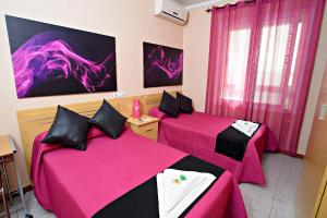 a room with two beds with pink sheets at Hostal Carrizo in Elda