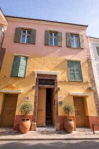 a building with two potted plants in front of it at Aurora Apartments in Mytilene