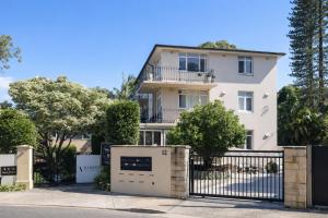 a white house with a black fence and trees at Sydney Harbour Side Waterfront Apartment in Sydney