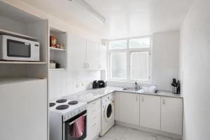 a white kitchen with a stove and a microwave at Sydney Harbour Side Waterfront Apartment in Sydney +17 photos
