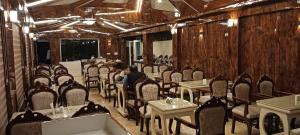 a restaurant with tables and chairs and a man sitting in the middle at Benzz Park Family Resort Kodaikanal in Kodaikānāl
