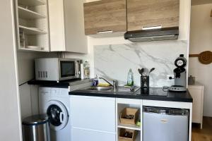 a kitchen with a sink and a microwave at L'escapade Sweet home - vue sur Mer et Dragon de Calais in Calais