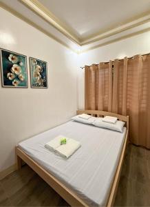 two beds in a bedroom with two pictures on the wall at Nielo's Apartment Door 4 in Dapitan