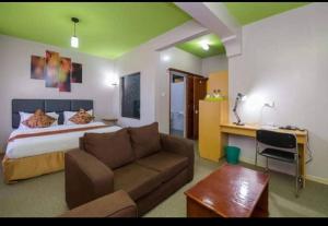 a bedroom with a bed and a couch in a room at Maple inn & Resort in Nairobi