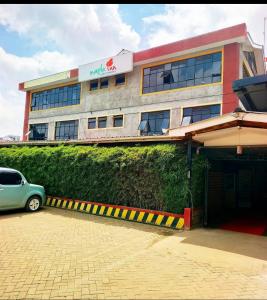 a building with a car parked in front of it at Maple inn & Resort in Nairobi
