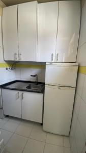 a kitchen with white cabinets and a sink and a refrigerator at Kamana Studio in Luanda