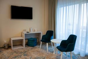 a room with two chairs and a table and a television at Fiald Hotel & Spa in Bacău