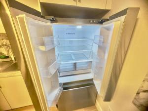 an empty refrigerator with its door open in a kitchen at Airport Haven Getaway in Dieppe