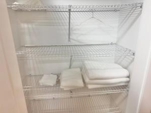 a refrigerator filled with white towels on a shelf at Airport Haven Getaway in Dieppe