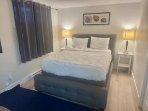 a bed in a bedroom with two lamps and a table at Airport Haven Getaway in Dieppe