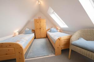 a attic room with two beds and a chair at Boje 15 in Schillig +12 photos