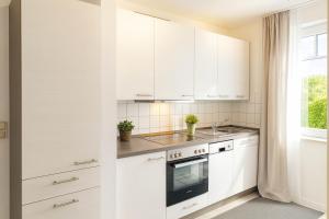 a kitchen with white cabinets and a sink at Boje 7 in Schillig
