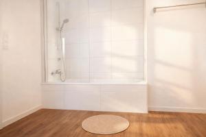 a white bathroom with a tub and a rug on the floor at Vogelkieker in Schillig +15 photos