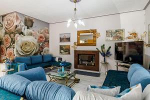 a living room with blue couches and a flower mural at Unique Filoxenia! in Skopelos Town