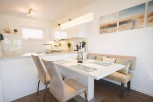 a white kitchen with a white table and chairs at Strandnah in Schillig +17 photos