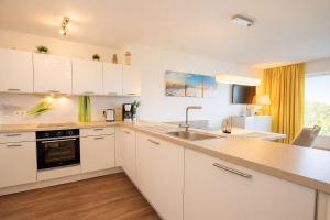 a kitchen with white cabinets and a sink at Strandnah in Schillig