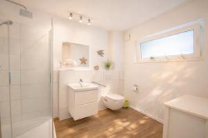 a white bathroom with a toilet and a window at Strandnah in Schillig