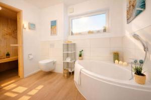 a white bathroom with a tub and a toilet at Leuchtfeuer in Schillig