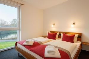 a bedroom with two beds with red pillows and a window at Waterkant in Schillig