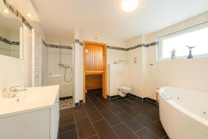 a bathroom with a tub and a toilet and a sink at Waterkant in Schillig +15 photos