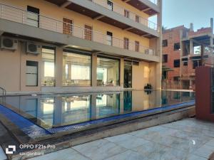 a large building with a swimming pool in front of it at Saisha Palace Hotel, Ganpatipule in Ganpatipule
