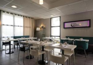 a dining room with tables and chairs and a tv at The Originals City, Hotel Novella Confort, Nantes Est in Carquefou