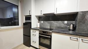 a kitchen with white cabinets and a black refrigerator at Piękna 20 Residence in Łomża
