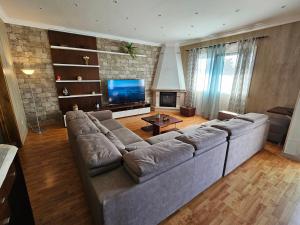a living room with a large couch and a television at Santa Maria Goldcrest House in Vila do Porto +8 photos